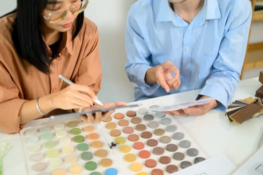 Creative design team discussing color samples and material swatches at co working space.