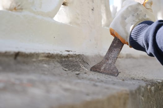 A worker carefully repairs a historic structure with tools in hand.