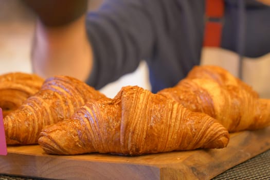 Delicious golden croissants arranged on a wooden surface at a bakery.