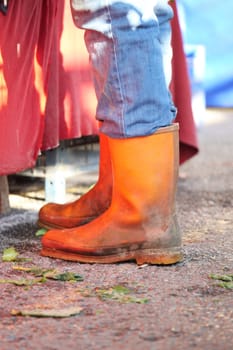 Colorful rubber boots stand on the ground at a busy market.