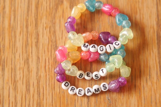 Brightly colored beads spell out uplifting words on a wooden table.