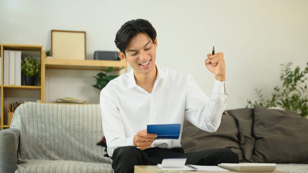 Excited man looking at bank passbook with a pleased expression, achieving a savings milestone.