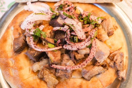 Grilled meat served on flatbread topped with onions and fresh herbs.