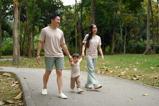 Young family walking along the path in a scenic park. Outdoor leisure and family bonding concept.