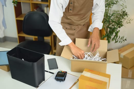 Online seller packaging an order into a cardboard box for shipment.