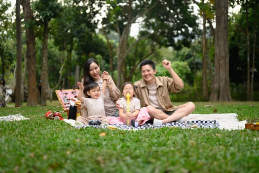 Happy family having a picnic in the park during summer weekend.