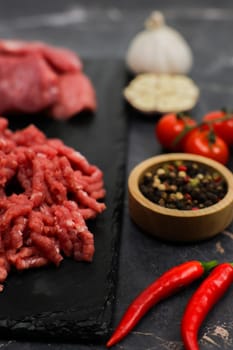 The concept of natural products, proper nutrition, diet, detox. Vertical photo on one side of beef meat minced and diced: on the other side there are spices and vegetables. High quality photo
