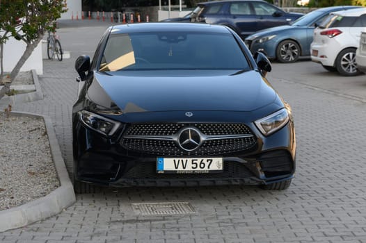 Gaziveren Cyprus -03.02.2025 Sleek black luxury sedan stands confidently in a contemporary parking area with modern architecture in view.