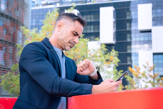 professional middle-aged businessman in a suit checking his smartphone and smartwatch. The modern city background highlights a fast-paced, connected lifestyle focused on productivity and efficiency.