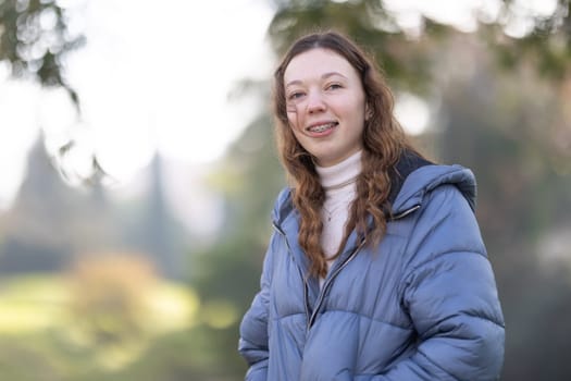 Portrait of smiling teenage girl wearing braces and winter clothes in park