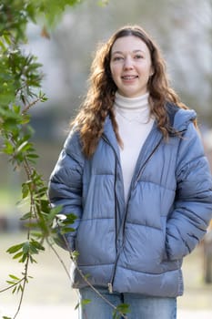 Portrait of a smiling young woman with curly hair wearing braces and a blue puffer jacket