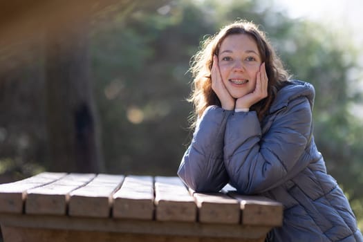 Happy teenager with dental braces smiling and posing with hands on face in a park