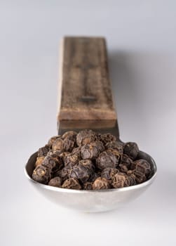 Perspective view of Raw organic black peppercorns or Dry black pepper seeds in stainless steel spoon isolated on the white background. use it as your Space for text, Design, Wallpaper and Poster, Selective focus.