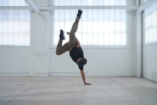 In a bright and spacious studio, a highly skilled breakdancer showcases their impressive dance talents
