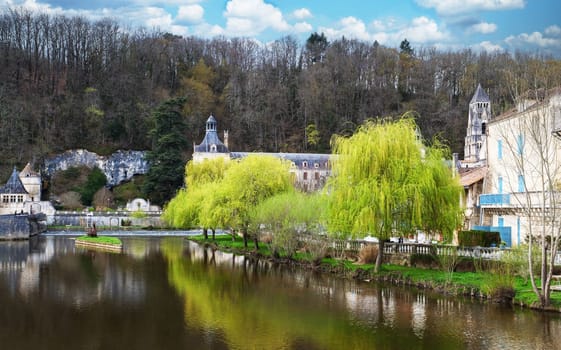 A beautiful river with a house on the right bank. The house is surrounded by trees and has a blue roof. The water is calm and reflects the trees and the house, Brandonne, France