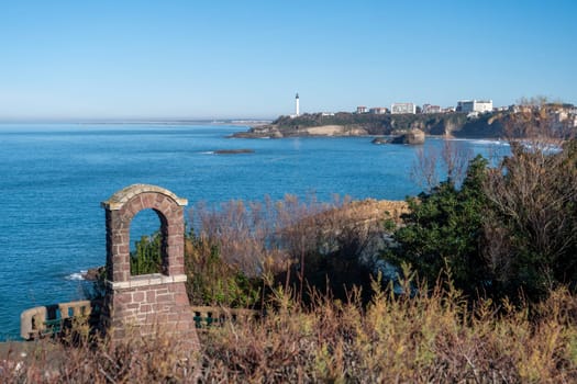 A view of the ocean with a lighthouse in the distance. The lighthouse is on a cliff overlooking the water. The scene is peaceful and serene, with the ocean and the lighthouse creating a sense of calm