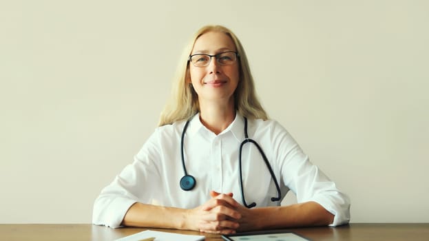 Caucasian middle-aged woman doctor working sitting at desk in clinic office
