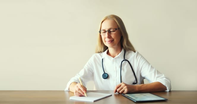 Caucasian middle-aged woman doctor working sitting at desk in clinic office
