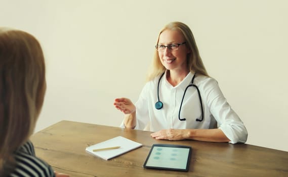 Woman doctor therapist talking to girl patient prescribes medications while sitting at desk in clinic office