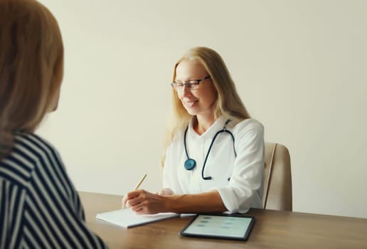 Woman doctor therapist talking to girl patient prescribes medications while sitting at desk in clinic office