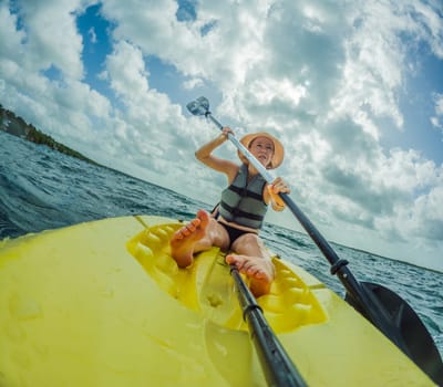 Unaltered woman tourist kayaking on the serene turquoise waters of Lake Bacalar, Mexico, surrounded by natural beauty. Adventure, relaxation, and outdoor travel concept in a peaceful tropical destination.