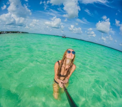 Woman standing in the crystal-clear waters of Lake Bacalar, Mexico, enjoying the serene beauty of the landscape. Tranquil moment in nature, outdoor escape, and relaxation concept.