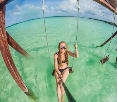 Woman standing in the crystal-clear waters of Lake Bacalar, Mexico, enjoying the serene beauty of the landscape. Tranquil moment in nature, outdoor escape, and relaxation concept.
