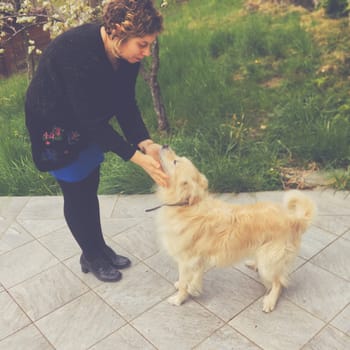 a caucasian woman plays with her pets in the garden. High quality photo