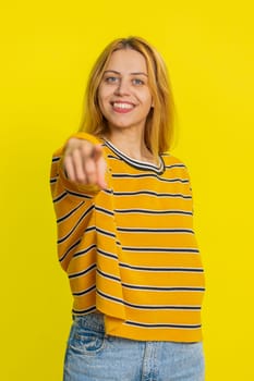 Hey you. Happy Caucasian young blonde woman smiling excitedly and pointing forward to camera, choosing lucky game winner, indicating to awesome you, promotion. Girl isolated on yellow background
