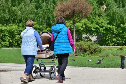 Moscow, Russia - 31 May. 2021. Two women walks with newborn in stroller in a park in Zelenograd