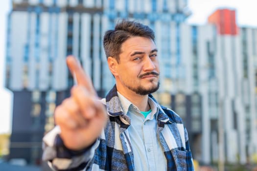 Displeased upset Caucasian man reacting to unpleasant awful idea, dissatisfied with bad quality, wave hand, shake head No, dismiss idea, dont like proposal. Mature adult guy traveler on urban street.