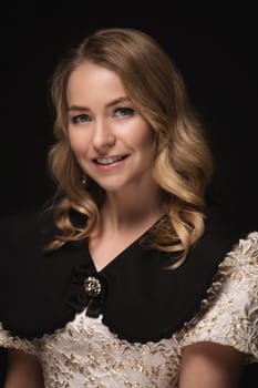 Beautiful blonde in a dress, portrait on a black background.