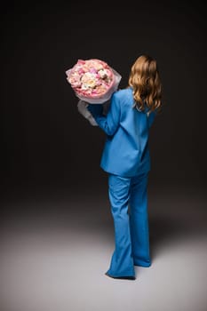 Beautiful girl fashion model with soft pink makeup poses in an elegant blue pantsuit. Fashion and beauty.