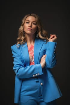 Beautiful girl fashion model with soft pink makeup poses in an elegant blue pantsuit. Fashion and beauty.