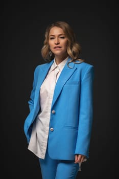 Beautiful girl fashion model with soft pink makeup poses in an elegant blue pantsuit. Fashion and beauty.