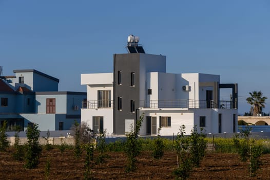 A beautifully designed house showcases sleek lines and contrasts with greenery under the vibrant sky in Cyprus.