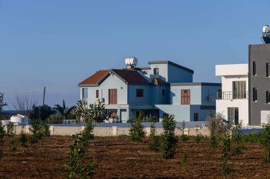 A charming blue house stands proudly against the backdrop of clear skies, embraced by green fields and tranquility.