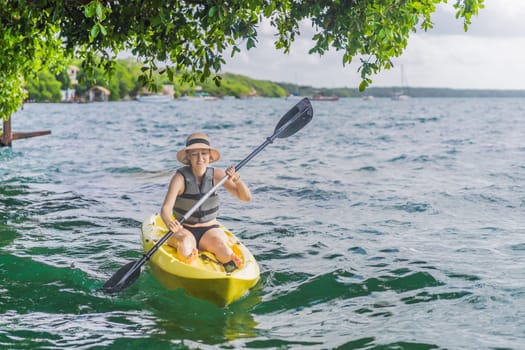 Woman kayaking on Bacalar Lake in Mexico. Adventure tourism in Quintana Roo, outdoor exploration, and water activities concept.