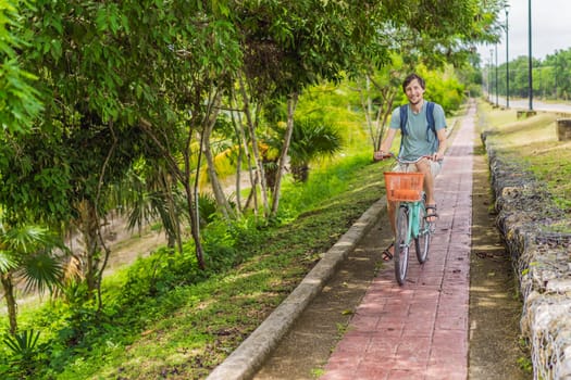 Man tourist cycling through the charming village of Bacalar, Mexico. Quintana Roo travel, scenic bike paths, and eco-friendly exploration concept.