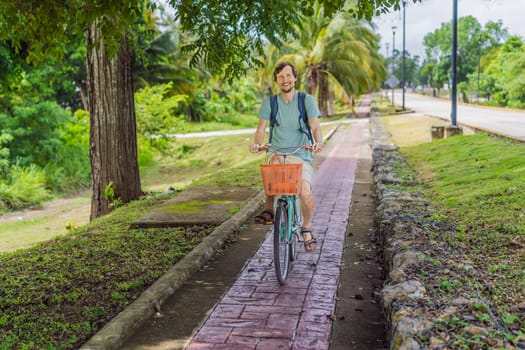 Man tourist cycling through the charming village of Bacalar, Mexico. Quintana Roo travel, scenic bike paths, and eco-friendly exploration concept.