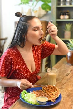Young woman eating waffles in a coffee shop