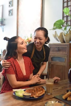 Young Vietnamese waitress smile and hug a friend customer