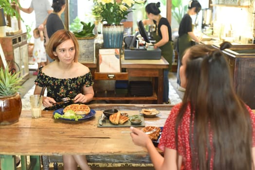 Young women chatting and eating waffles in a cafe