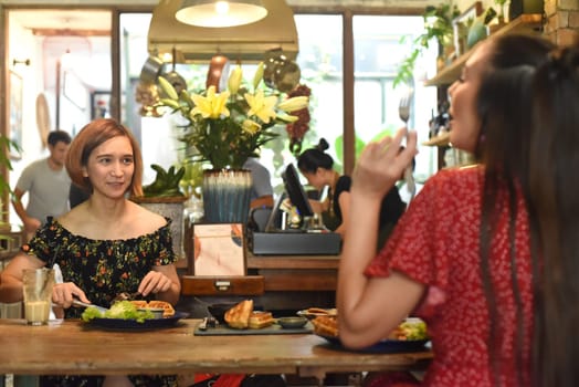 Young women chatting and eating waffles in a cafe