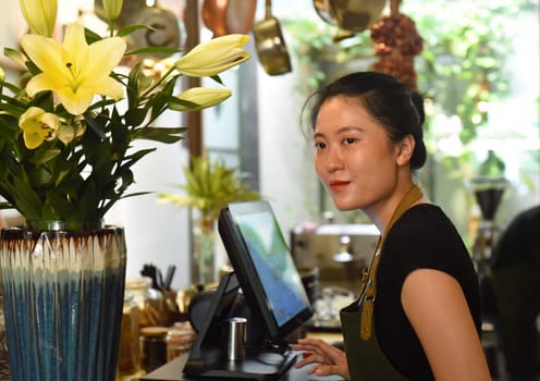 Young Vietnamese waitress working with check out machine