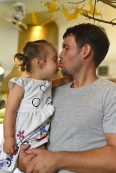 Young father kissing his daughter and holding her at his hands