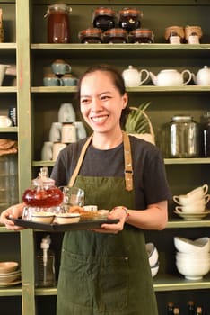 Vietnamese young woman serving tea in a coffee shop