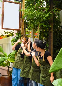Vietnamese coffee shop team smiling and showing the empty sign, standing together against a cafe