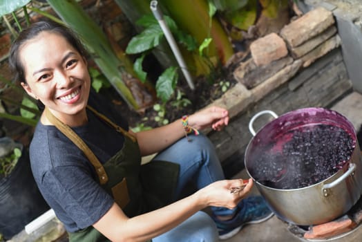 Young Vietnamese woman cooking a mulberry jam in a big saucepan