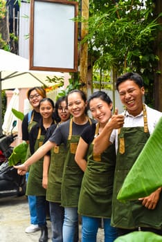 Vietnamese coffee shop team smiling and standing together against a cafe
